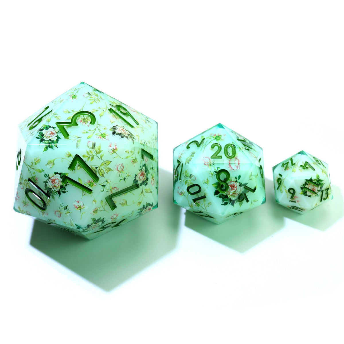 33 mm mint green resin d20 with tiny flowers and green numbers, beside two smaller d20s